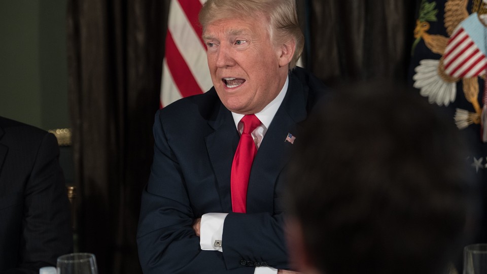 President Trump talks with his arms folded