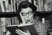 A black-and-white photo of a shocked woman reading a book