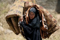 An Iraqi woman carries a mattress and a blanket while she flees her home in Mosul in 2017