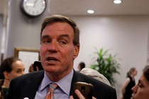Mark Warner speaks as reporters hold up cellphones to record him.