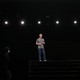 Mark Zuckerberg on a stage being photographed and lit by spotlights