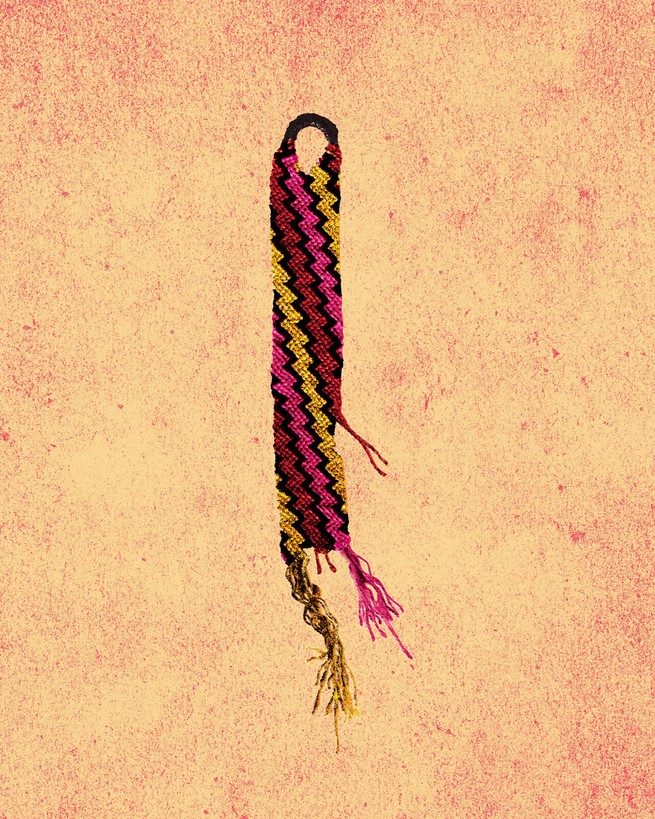 a hand-knotted friendship bracelet with yellow, pink, red, and black zigzags that has frayed and broken