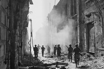 A photograph of soldiers in a street full of rubble