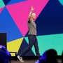 Mark Zuckerberg raises his hand while walking across a stage.