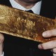 Color photograph of a person's hands holding a bar of gold.