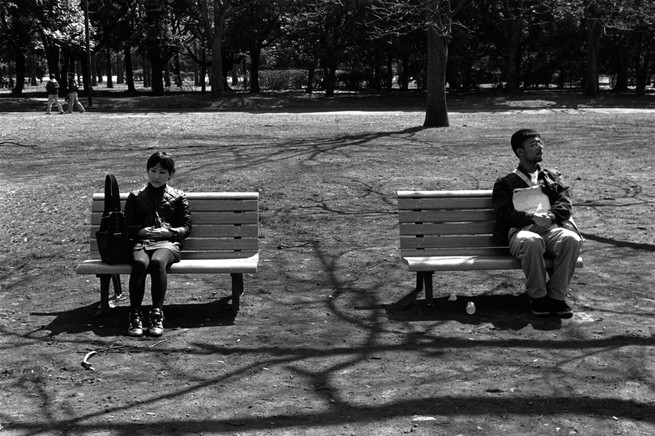 people sitting far apart on benches