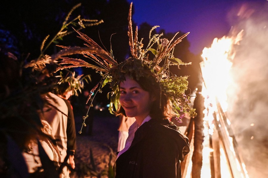 A woman wearing a wreath attends a bonfire celebration.