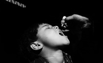 A child opens his mouth to receive the oral polio vaccine