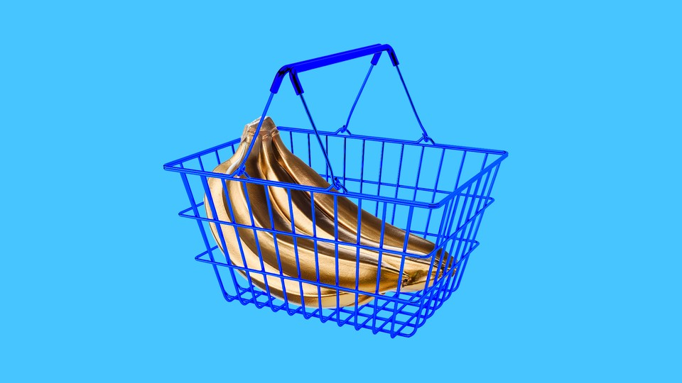 Gold-colored bananas inside a blue shopping basket against a baby-blue background