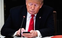 A photograph of Donald Trump using a smartphone.