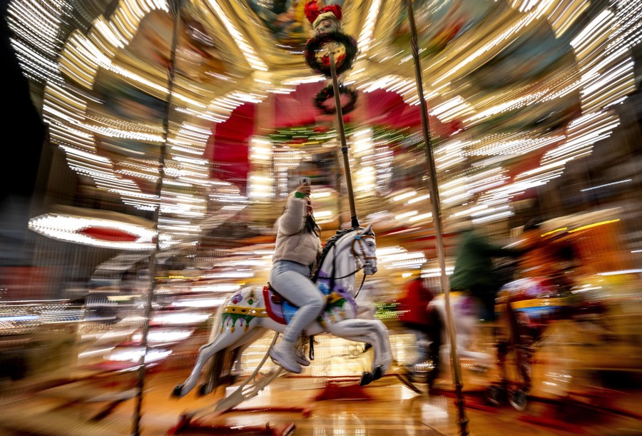 A girl uses her mobile phone as she rides on a merry-go-round.