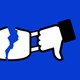 Facebook thumbs-up and thumbs-down logos, ripping apart a face mask.