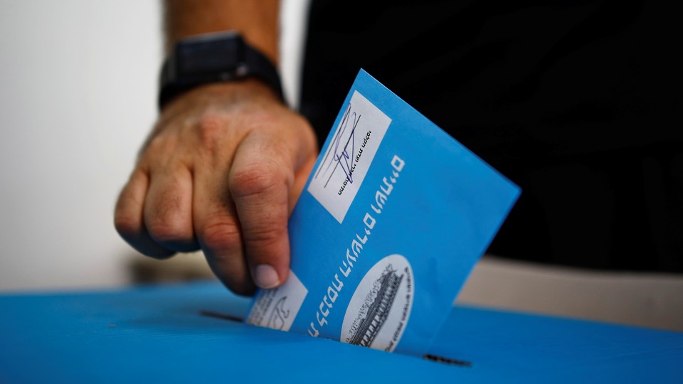 A man's hand is pictured dropping his vote into a ballot box in an Israeli general election.