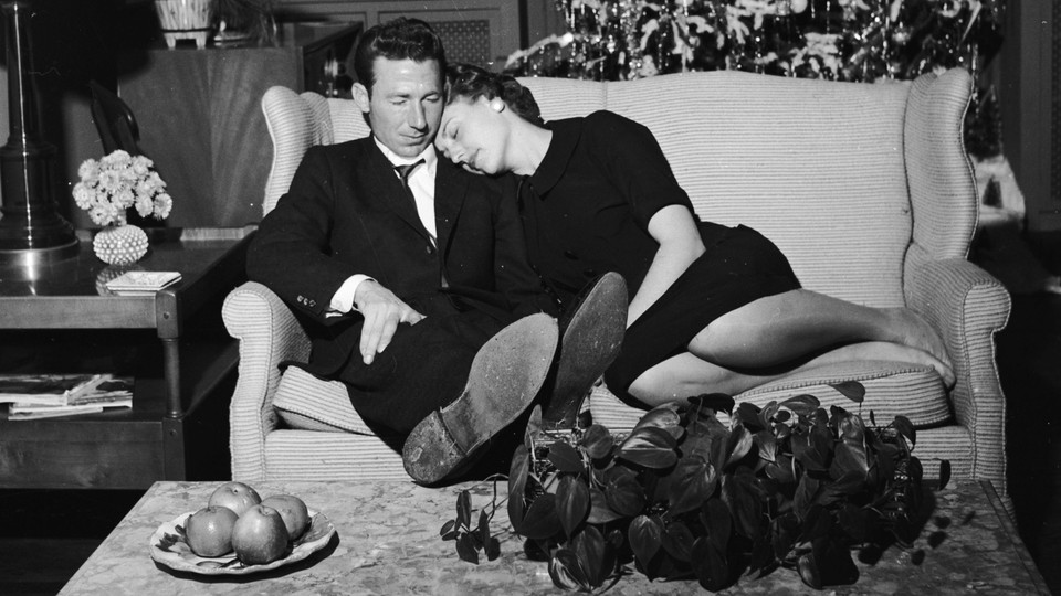 A couple relax on the couch, in black and white