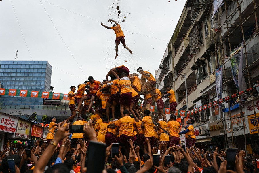 A person falls above a collapsing tower made of people standing on one another's shoulders.