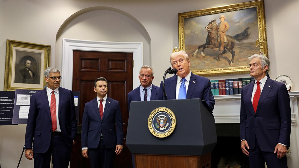 Jay Bhattacharya, Marty Makary, Robert F. Kennedy Jr., Donald Trump, and Mehmet Oz stand behind a podium in the Roosevelt Room of the White House