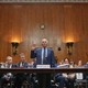 Photograph of Dr. Anthony Fauci standing up in a government hearing with his right hand raised.