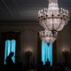 Trump speaks in a room with big chandeliers