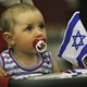A baby holds an Israeli flag.