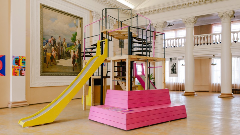 A colorful playground with a slide is placed in an old ballroom.