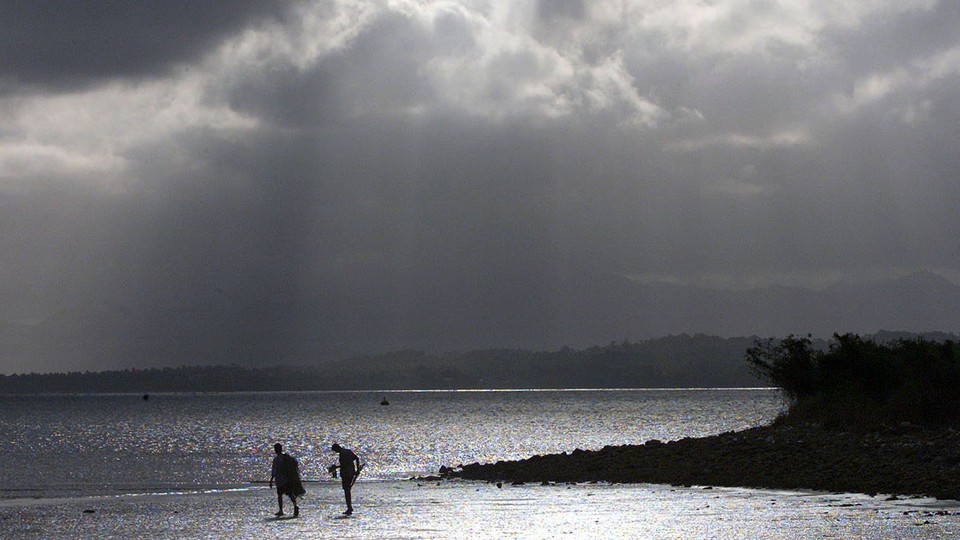 An afternoon storm looms above fishermen in Suva, Fiji