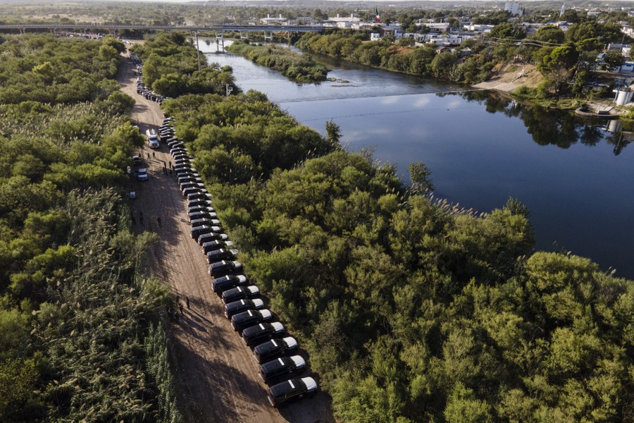 A long line of parked Texas Department of Safety vehicles is seen along the Rio Grande river.