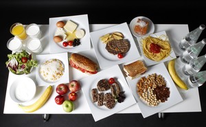 A table containing salad, fruit, water, pasta, meats, sandwiches, cheese, eggs, juice, and milk