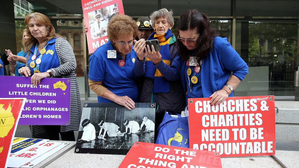Protesters watch a live-stream of an Australian judge handing down his sentence for Cardinal Pell.