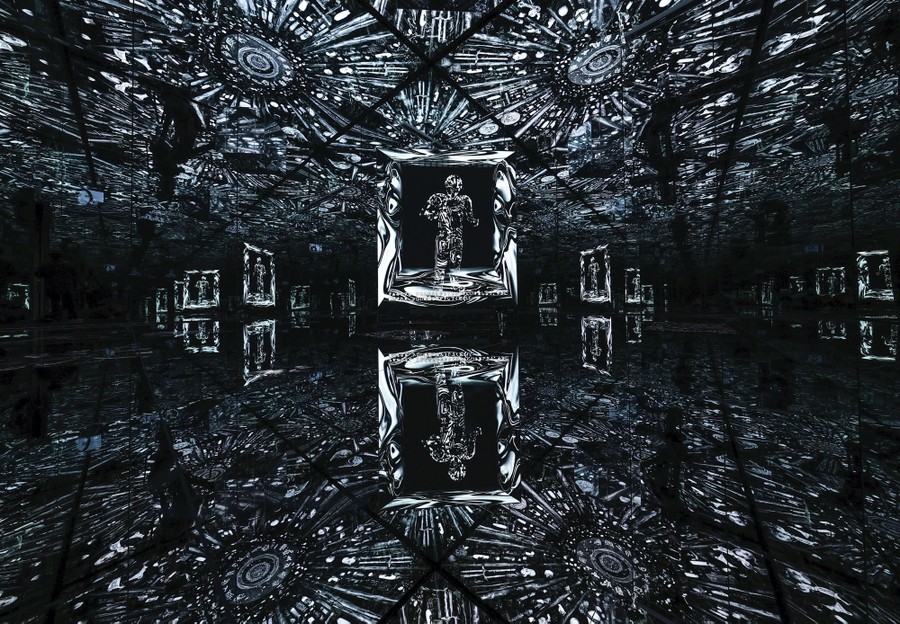 An art exhibit, made up of many mirrors and lights, with a human figure in a frame at center