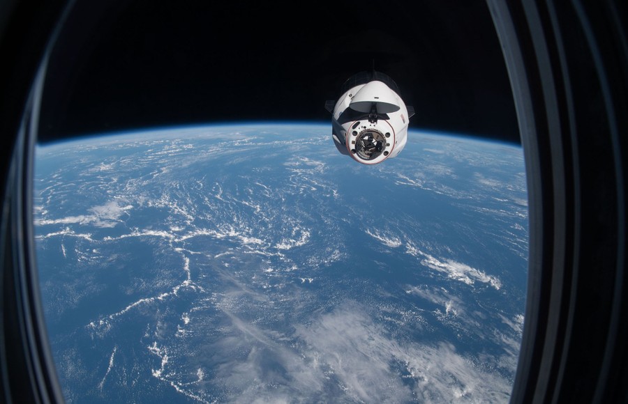 A spacecraft carrying astronauts is seen through the window of another spacecraft docked with the International Space Station.