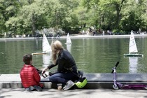 A mother and child look at miniature sailboats. 