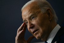 A photo of Joe Biden touching his temple with one hand during his remarks