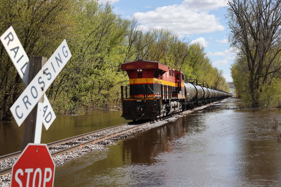 A train travels along tracks surrounded by floodwater.