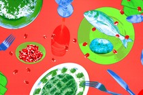 A top-down view of a dining table including fish, potatoes, cutlery, and glasses