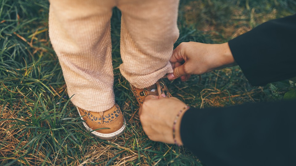 Parent tying child's shoe