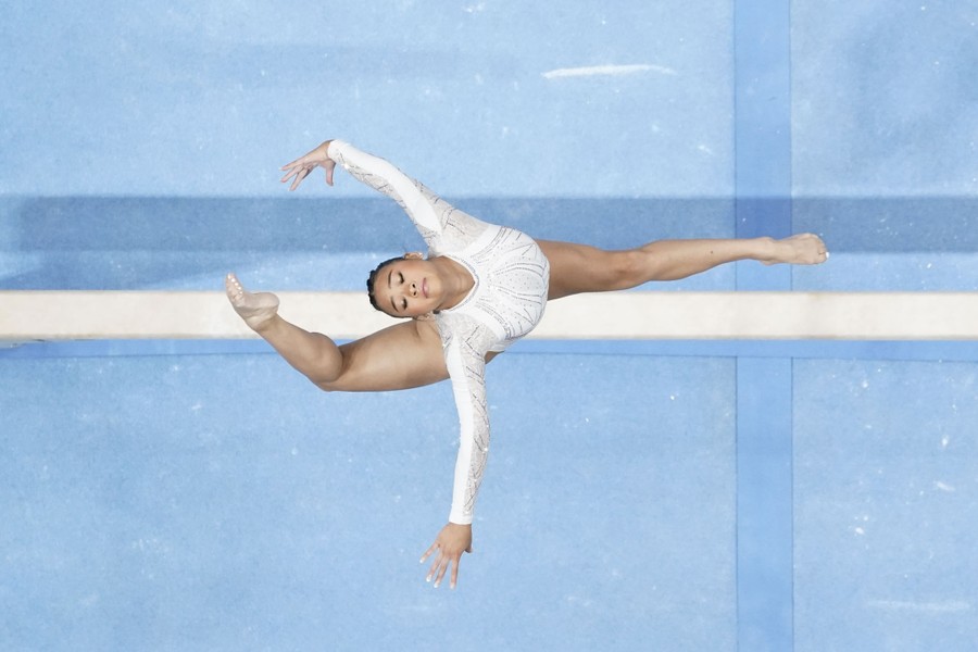 A top-down view of a gymnast performing a jump above a balance beam