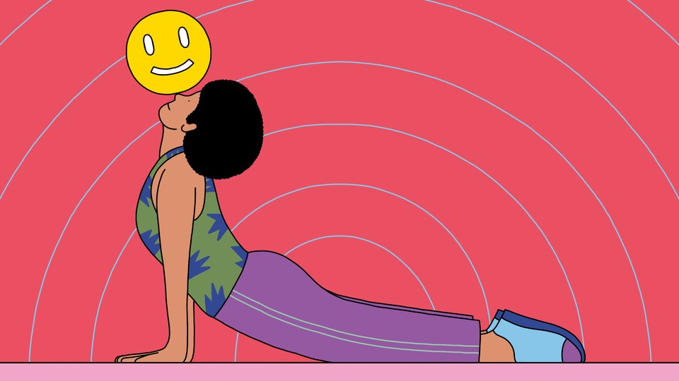 A woman in the upward-dog yoga pose balancing a smiley face on her nose