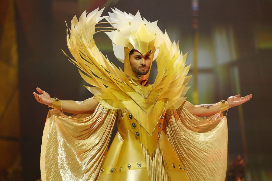 A model poses, wearing an elaborate gold-colored costume.