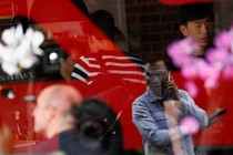 A man is reflected in a window as he uses his mobile phone