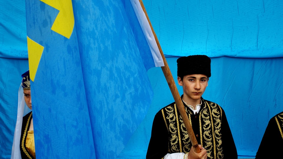 A young Crimean Tatar holds a flag.