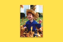 A young boy plays in a pile of leaves.