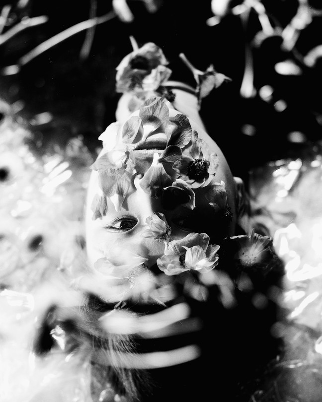 An upside-down photograph of a woman whose face is covered in flowers