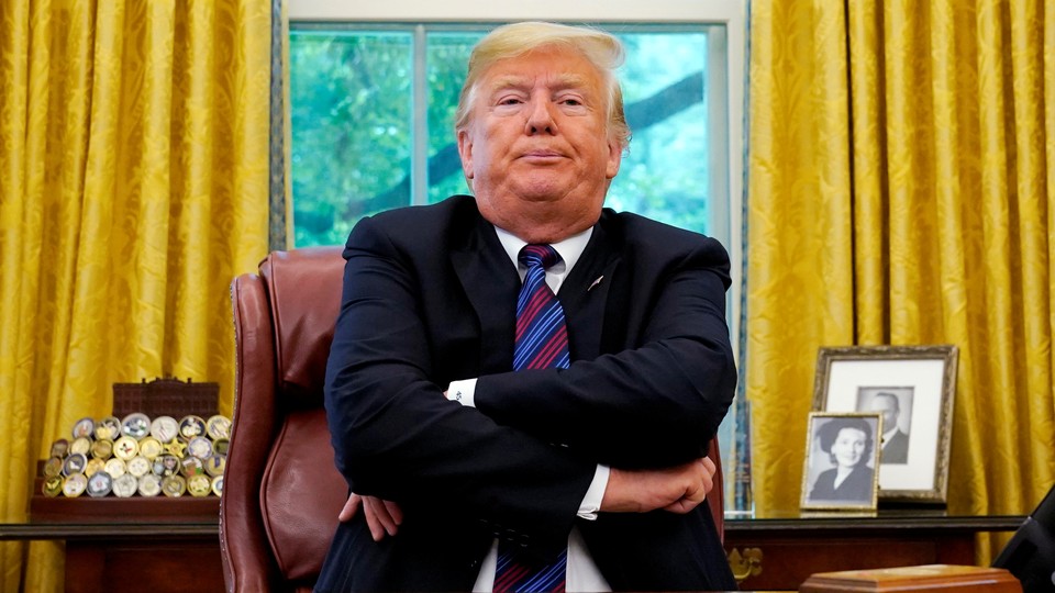Trump sits at his desk with his arms crossed while announcing the new trade deal with Mexico.