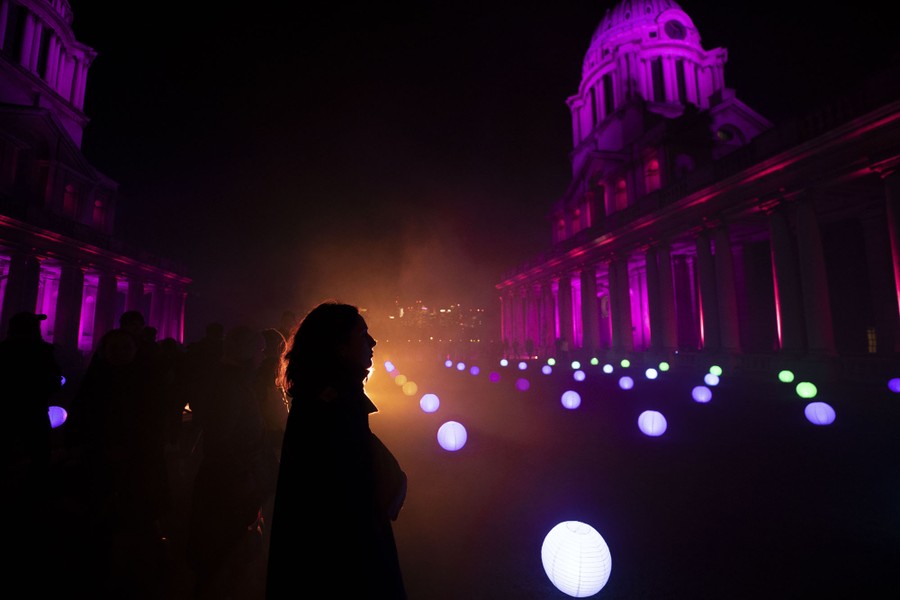 Lights shine during a night display among columned buildings.