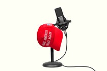 A red “Make America Great Again” cap resting on a podcast microphone