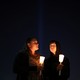 People hold candles at a vigil.