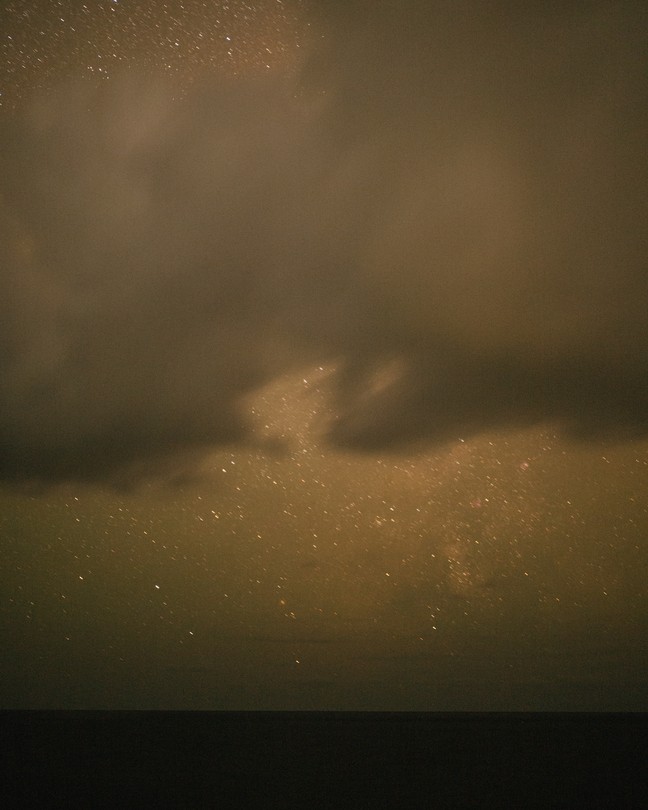 A cloudy green-gray sky over a stretch of dark water