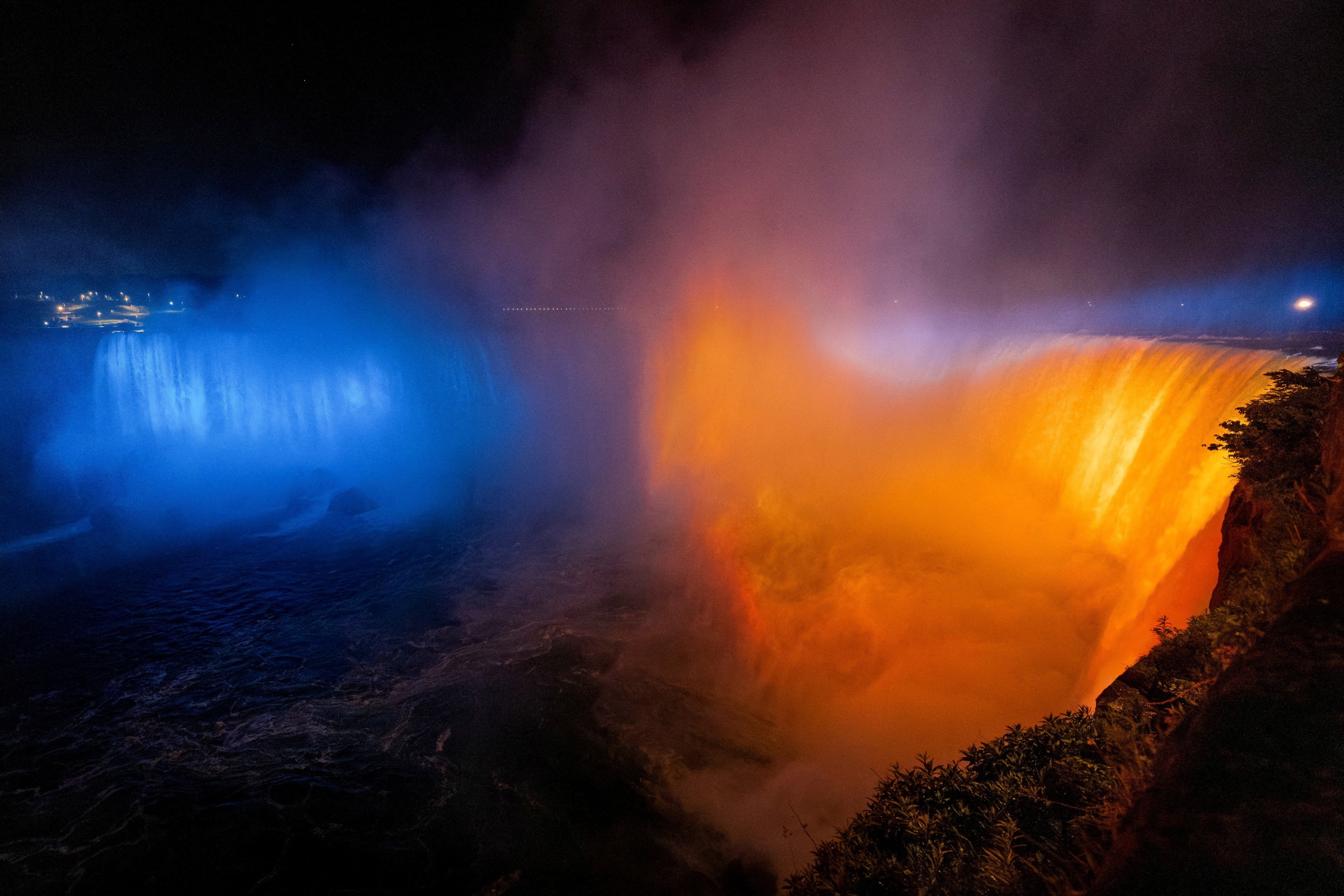 Niagara Falls, seen at night, lit up in blue and yellow colors