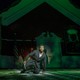Actor in green light kneeling on ground with a knife