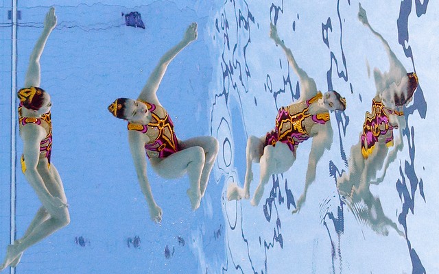 Two Japanese artistic swimmers wearing pink-and-orange suits compete at the Tokyo Olympics.